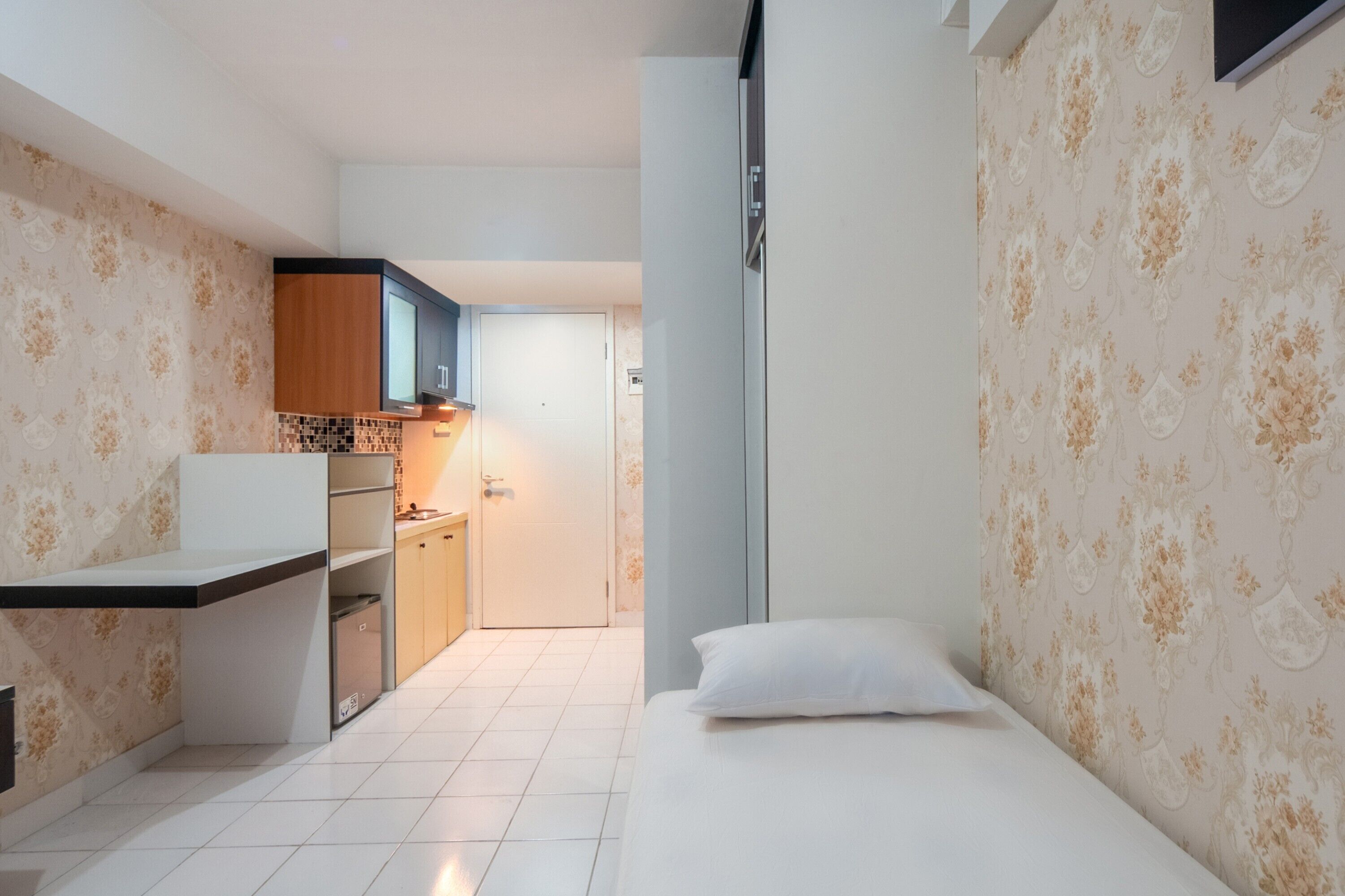 A compact room with a bed, a kitchenette, and a bathroom.