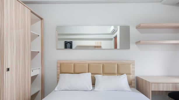 Een moderne hotelkamer met een bed, een grote spiegel en ingebouwde planken.