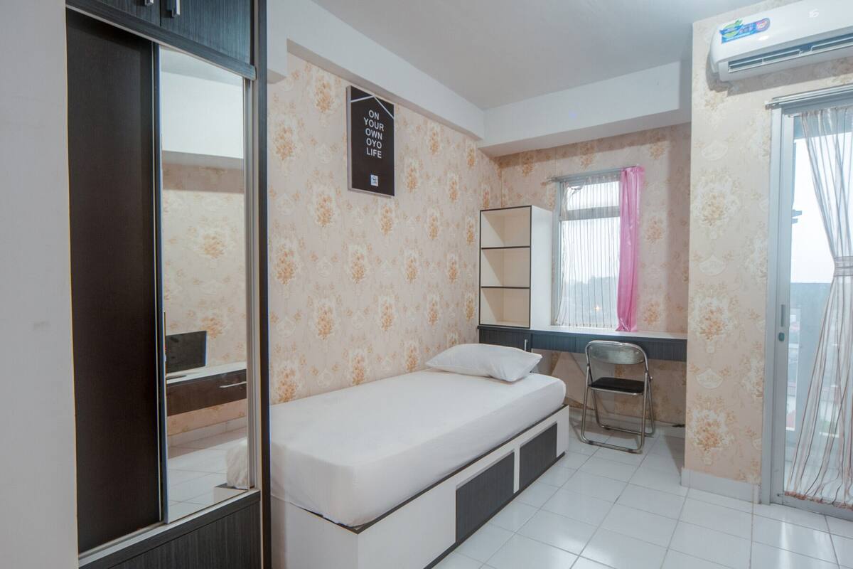A compact bedroom with a single bed, a wardrobe, a desk, and a chair.