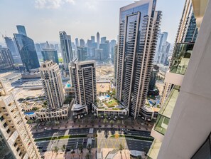 A high-rise residential building complex with multiple balconies, a central courtyard, and a view of the surrounding cityscape. - The Elevated Abode 1BHK Apt in Downtown (Dubai)