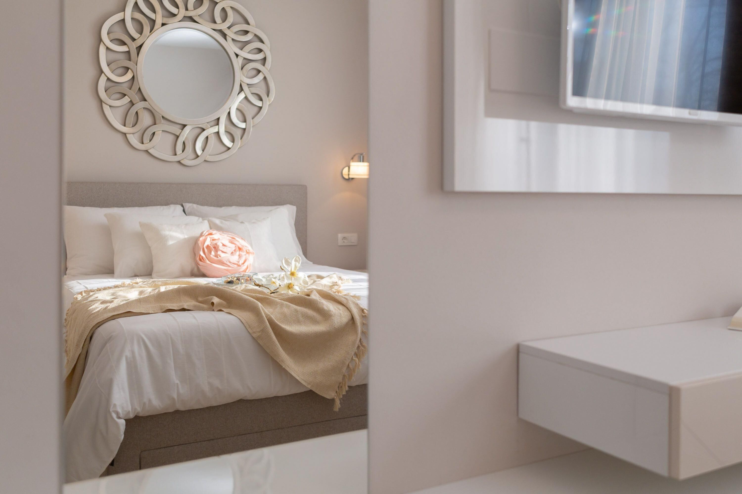 Une chambre à coucher comprenant un lit, une table de chevet, un miroir et un téléviseur fixé au mur.