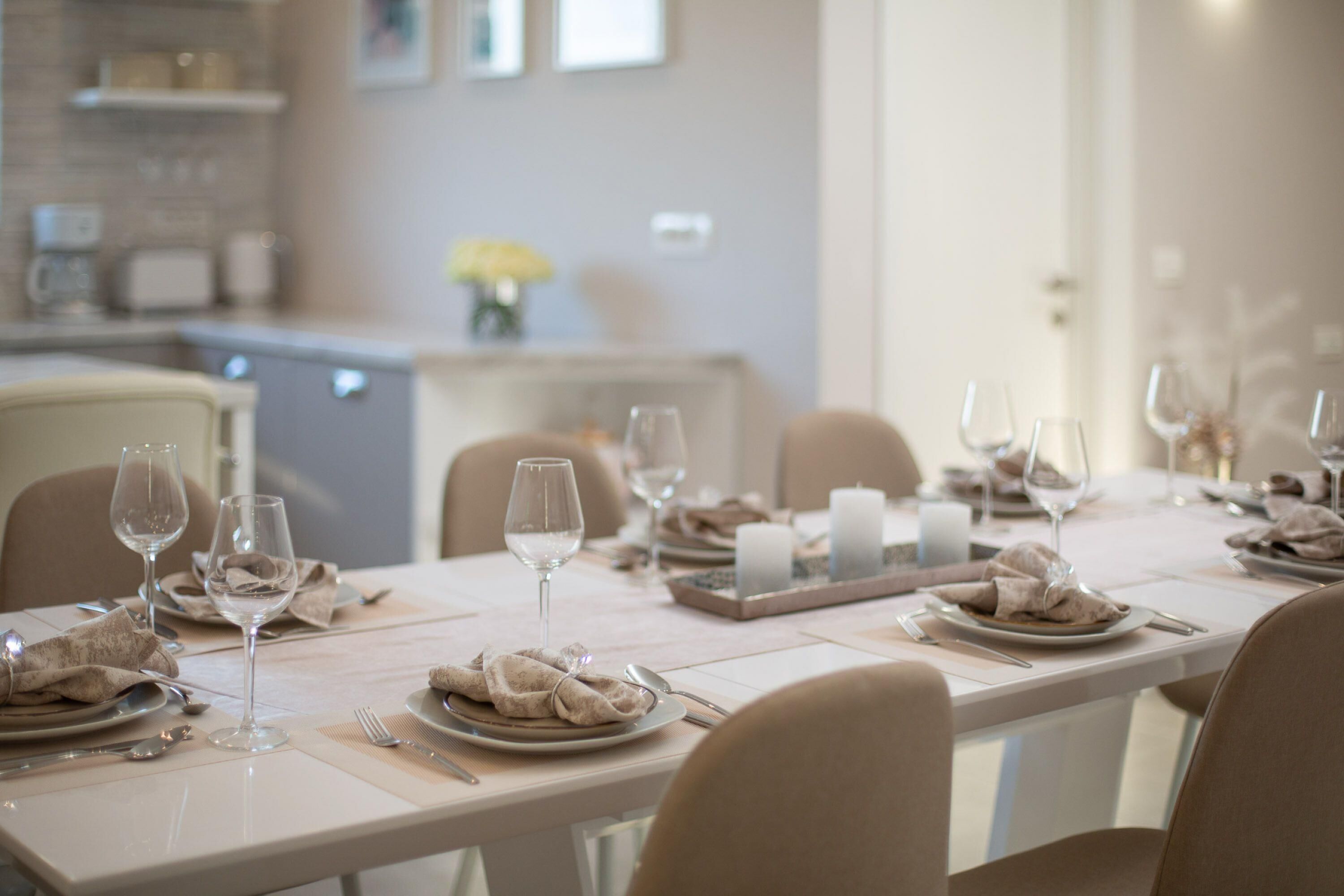 Een eettafel gedekt met wijnglazen, borden en servetten.