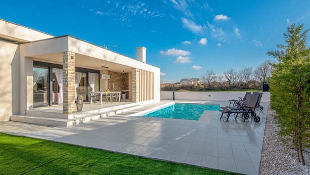 Ein modernes Haus mit Swimmingpool, Sitzgelegenheiten im Freien und freiem Blick auf die umliegende Landschaft.