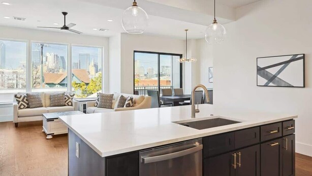 A modern kitchen with a large island, dark cabinetry, and pendant lighting. - 3-BD Luxury Living w Rooftop Garden Views (Dallas)