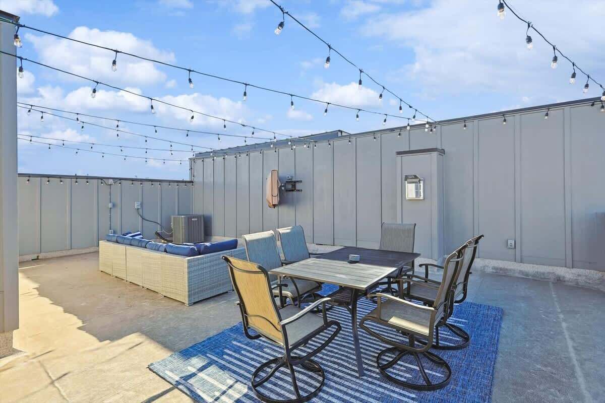 An outdoor patio area with a table and chairs, a sofa, and string lights.