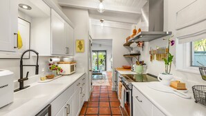 Een moderne keuken met witte kasten, een roestvrijstalen fornuis en een betegelde vloer.