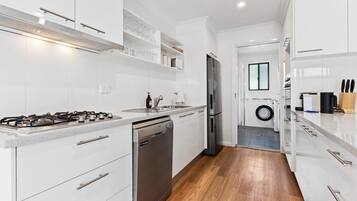 Una cucina moderna con mobili bianchi, elettrodomestici in acciaio inossidabile e pavimento in legno.