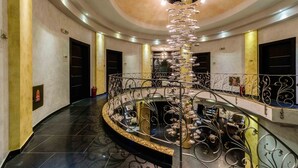 A grand, curved staircase with ornate metal railings and a chandelier. - Chateau Rond Boutique Hotel & Spa (Almopia)