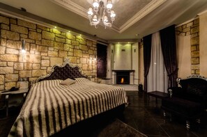 A bedroom with a stone wall, a fireplace, a bed with a striped blanket, and a dark-colored sofa.