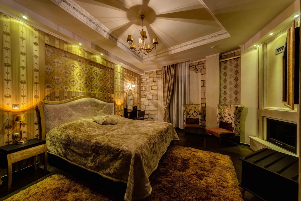 Une chambre à coucher luxueuse avec un grand lit, un lustre et une cheminée.