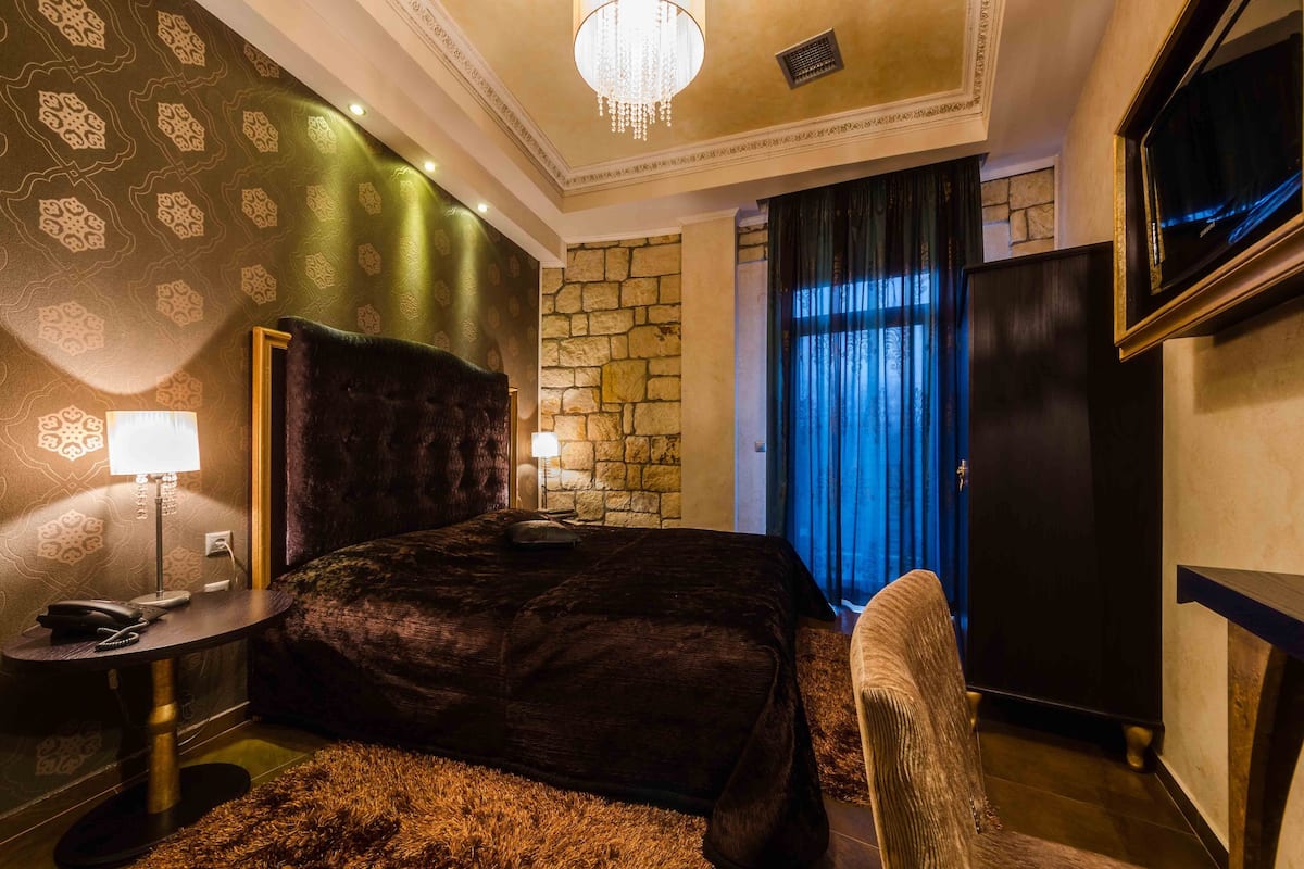 Une chambre d’hôtel avec un grand lit, un mur décoratif en pierre, un lustre et un téléviseur.