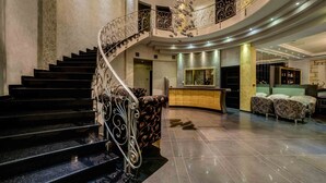 A grand lobby with a curved staircase, a reception desk, and seating area. - Chateau Rond Boutique Hotel & Spa (Almopia)