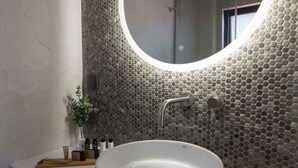 A bathroom with a round mirror, white sink, and hexagonal patterned wall tiles. - GV Sivota Luxury Villa - SL2022 (Igoumenitsa)
