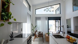 A modern kitchen with a dining area, large windows, and a view of the outdoors. - GV Sivota Luxury Villa - SL2022 (Igoumenitsa)