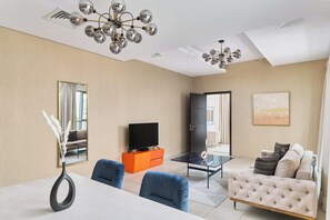 A modern living room with a sofa, a TV, a dining table, and a chandelier. - BellaVista - Spectacular - 2 BR Penthouse - Boulevard Central - Panoramic Terrace & Burj Khalifa Vie (Dubai)