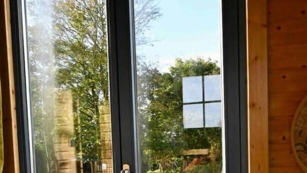 A room with a large sliding glass door leading to an outdoor area with a wooden deck and a table with a potted plant.
