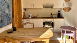 A compact kitchen with white cabinets, a wooden table, and a small purple chair. - Mecklenbü mit Teich, Kamin, Sauna und Hotpott (Dargun)
