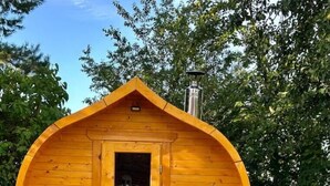 A wooden cabin with a pitched roof, a door with a window, and a chimney. - Mecklenbü mit Teich, Kamin, Sauna und Hotpott (Dargun)