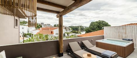 A rooftop terrace with a wooden pergola, lounge chairs, a hot tub, and a view of the cityscape.