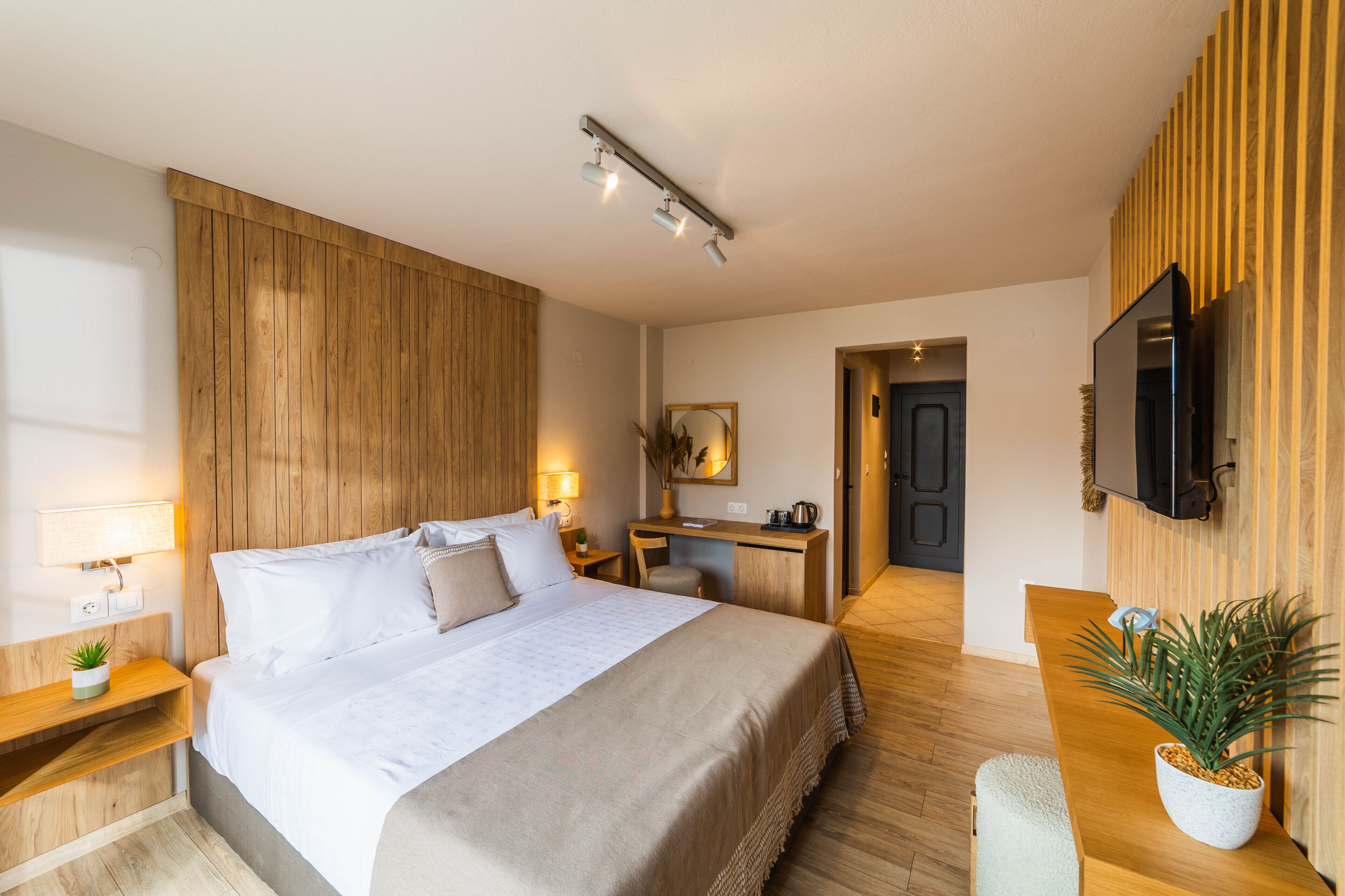 A modern hotel room with a large bed, bedside tables, a desk, and a TV.