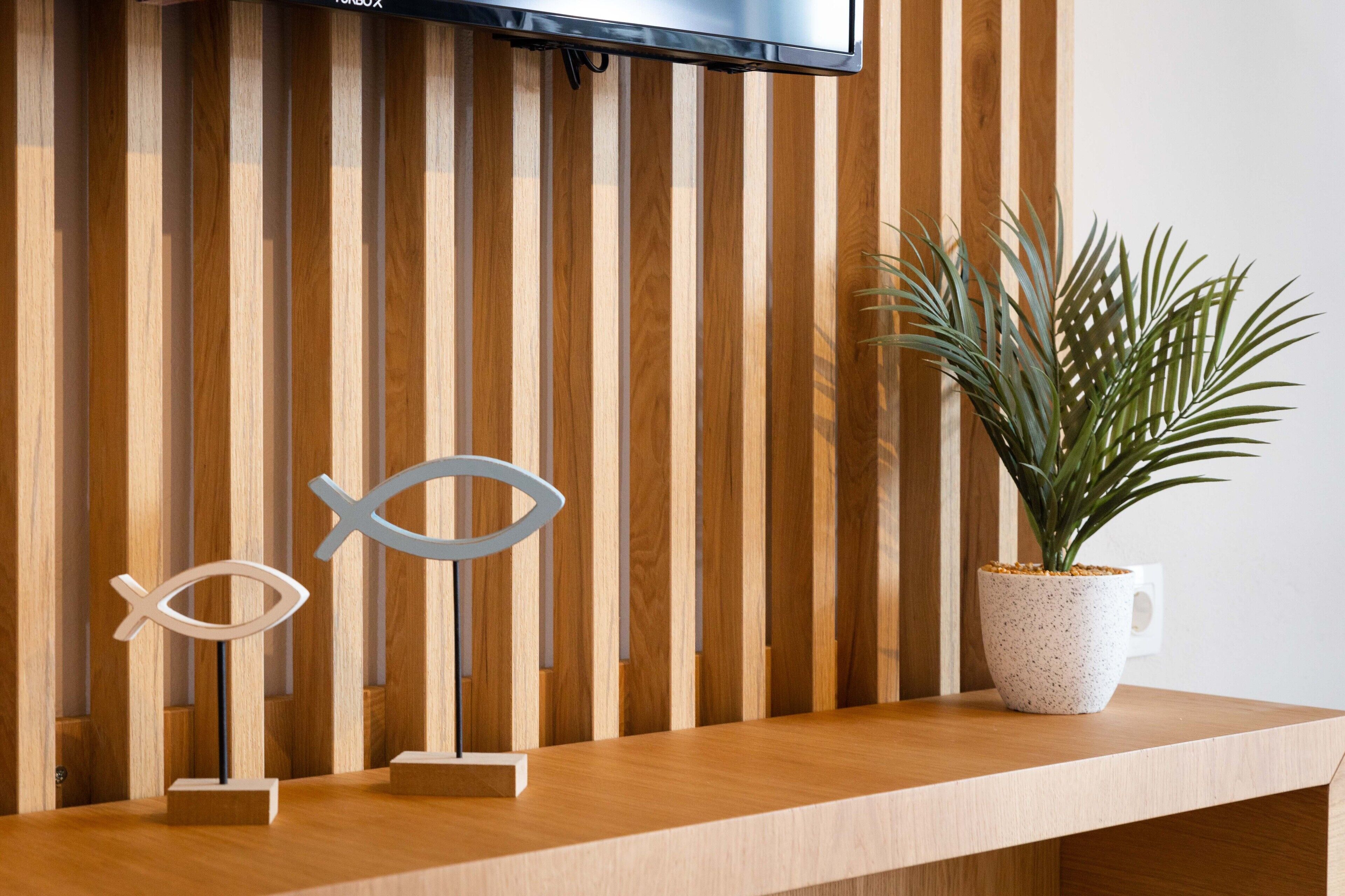 A wooden reception desk with a television mounted above it, a potted plant, and two fish-shaped decorations.