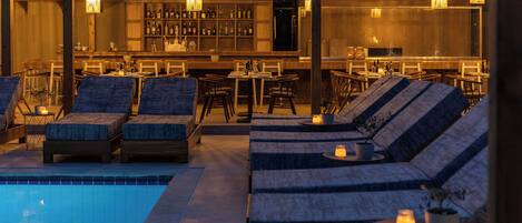 Un área junto a la piscina con sillones de descanso y un bar.