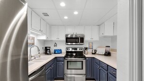 Una cocina moderna con electrodomésticos de acero inoxidable, armarios blancos y una alfombra gris.