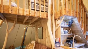 A wooden interior with a loft bed, a sofa, and a kitchen area. - Torre Cider Farm (Watchet)