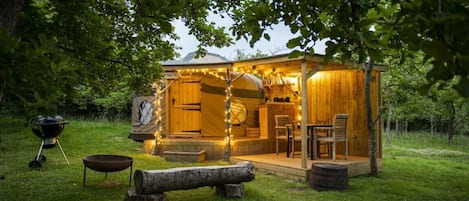 A rustic wooden cabin with a porch, a grill, and outdoor seating.