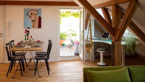 Ein Essbereich mit Holztisch und Stühlen, einem grünen Sofa und einem Bild an der Wand.