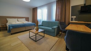 Een moderne hotelkamer met een bed, bank, salontafel, televisie en bureau.