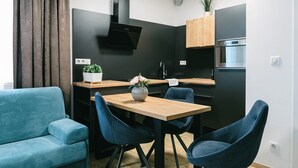 Een moderne keuken met een eethoek, met een houten tafel, blauwe stoelen, een zwarte afzuigkap en een inbouwoven.