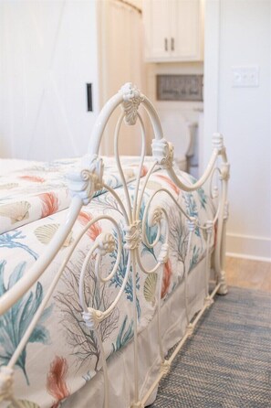 A bed with a floral bedspread and a white metal frame. - Pelican`s Perch at River Rocks Plantation (Guntersville)