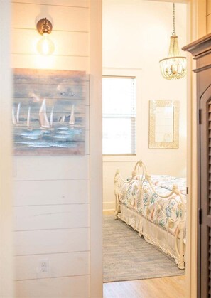 A bedroom with a bed, a painting, a chandelier, and a window. - Pelican`s Perch at River Rocks Plantation (Guntersville)