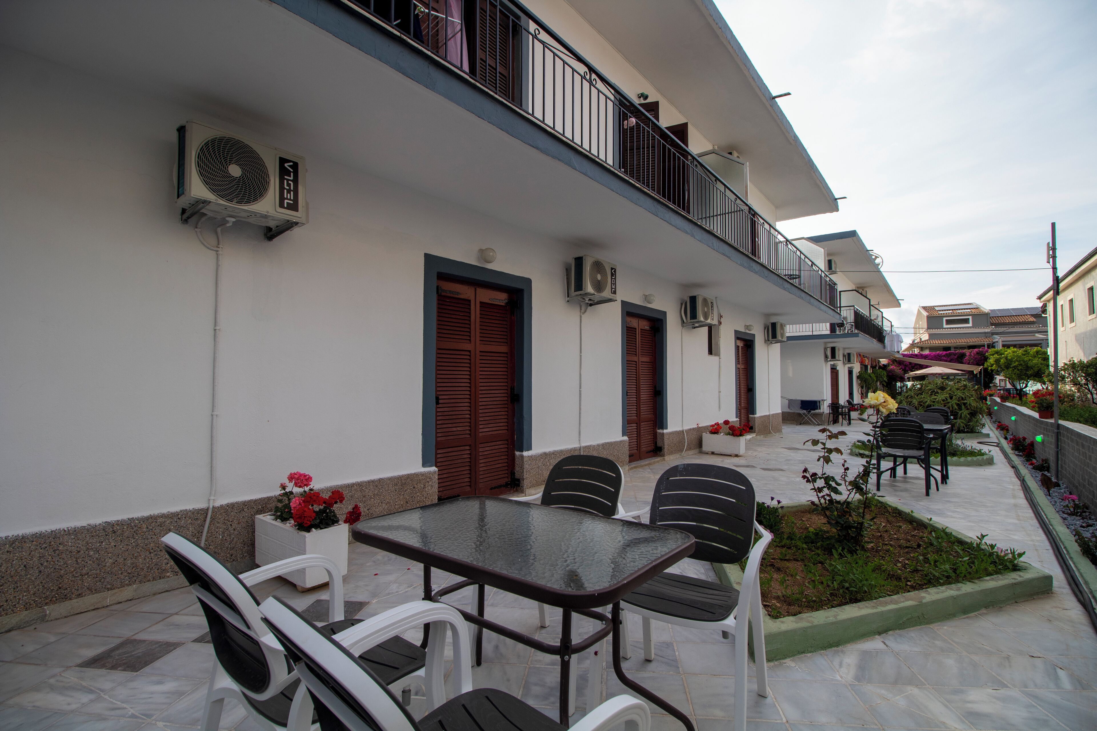 A courtyard with a table and chairs, air conditioning units, and a small garden area.