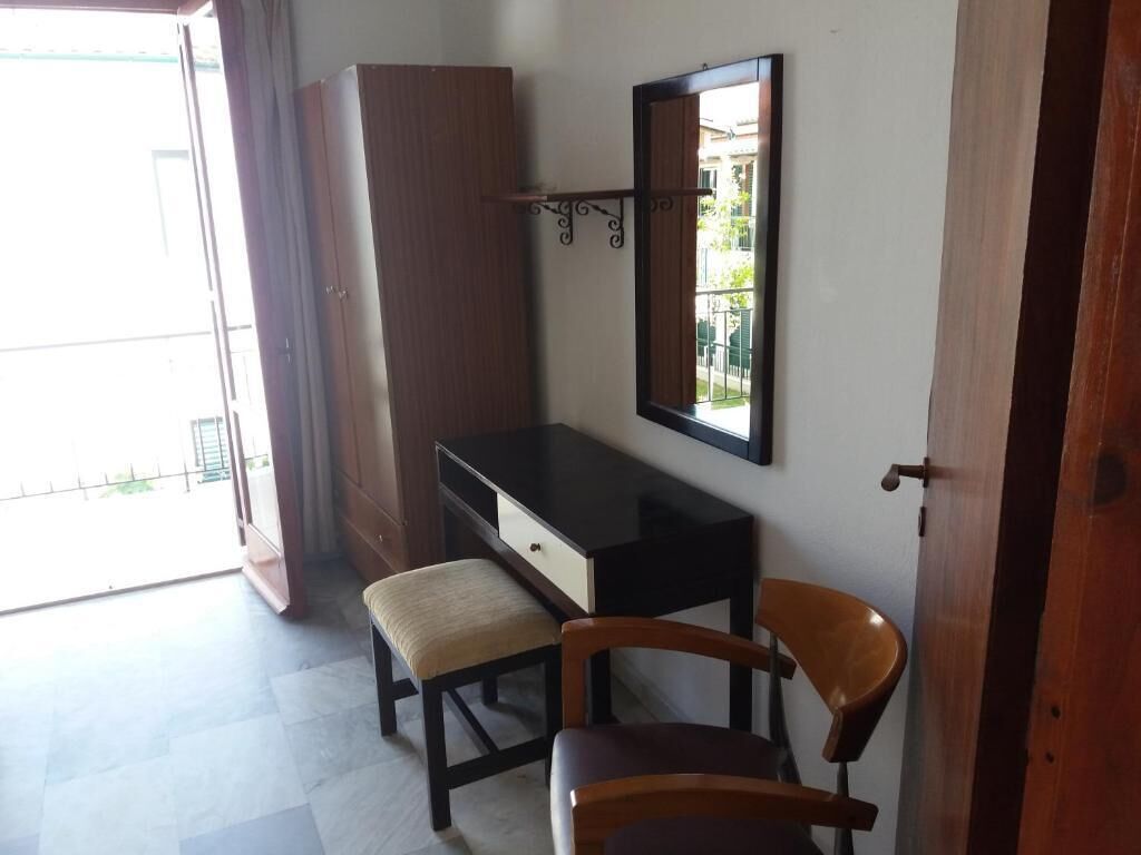 A room with a desk, two chairs, a mirror, and a wardrobe.