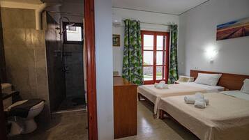Une chambre d’hôtel avec une douche, deux lits, un bureau et une fenêtre avec des rideaux.