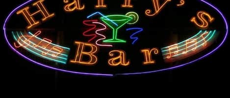 A neon sign for Harry's Bar with a martini glass and musical notes.