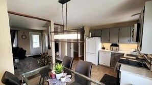 Una cucina moderna con mobili bianchi, un frigorifero e un'area pranzo con tavolo e sedie in vetro.