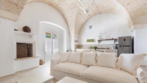 A spacious living room with a high arched ceiling, a white sofa, a coffee table, and a fireplace. - 3646 Casal 800 by Perle di Puglia (Ostuni)