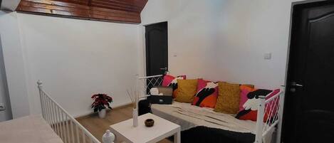 Una habitación acogedora con un sofá blanco, una mesita pequeña y una lámpara en el techo.