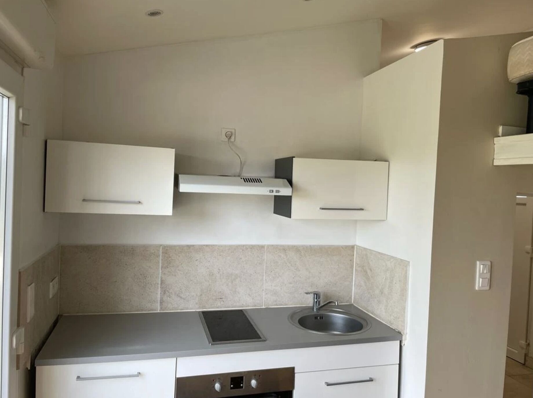 A modern kitchen with white cabinets, a stainless steel sink, and a built-in range hood.