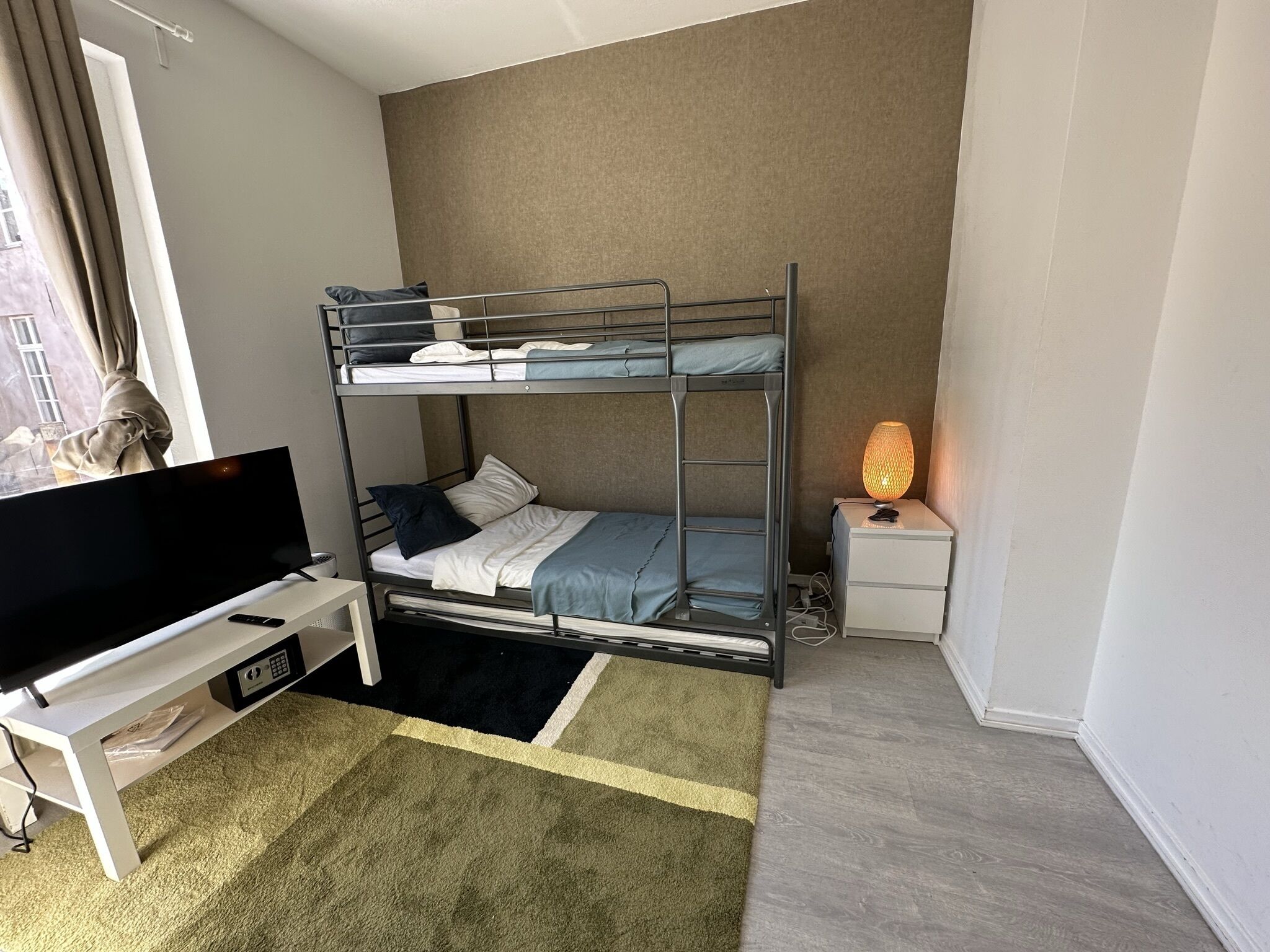 A bunk bed with a TV and a bedside table with a lamp.