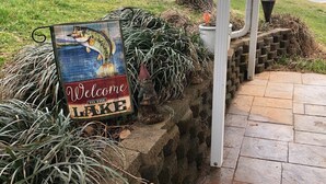 Señal de bienvenida a un lago con una caña de pescar y una estatua de gnomo.