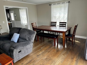 A dining area with a wooden table and chairs, a grey sofa, and a wooden bench. - 3br/2ba APT, sleeps 7, comfortable and spacious for whole family to spread out (Hickory)