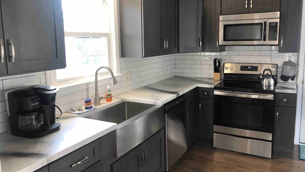 A modern kitchen with dark cabinets, stainless steel appliances, a double sink, and a coffee maker. - 3br/2ba APT, sleeps 7, comfortable and spacious for whole family to spread out (Hickory)