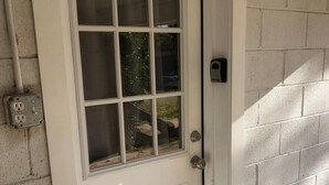 A white door with a glass panel, a doorbell, and a mailbox on the wall. - Bright open studio apartment with king bed and queen sofabed. Walk to local shops and restaurants. (Hickory)