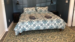 A bedroom with a large bed, dark blue walls, and patterned bedding. - Bright open studio apartment with king bed and queen sofabed. Walk to local shops and restaurants. (Hickory)