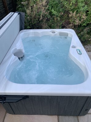 A rectangular hot tub with a white exterior and a grey interior, surrounded by greenery. - Red Squirrel Pod with Hot Tub - perfect for relaxing in countryside near Oban (Oban)