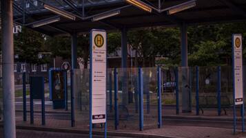 Eine Bushaltestelle mit Unterstand, ein Schild mit der Aufschrift 'Rhein-Mosel-Halle Bushaltestelle A' und ein 'koyeb'-Logo.